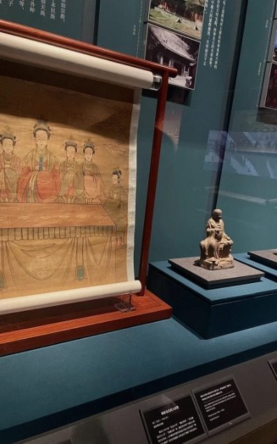 The Capital Museum-Museum Guide-Beijing The museum display case features an ancient Chinese painting and two small Buddha statues.