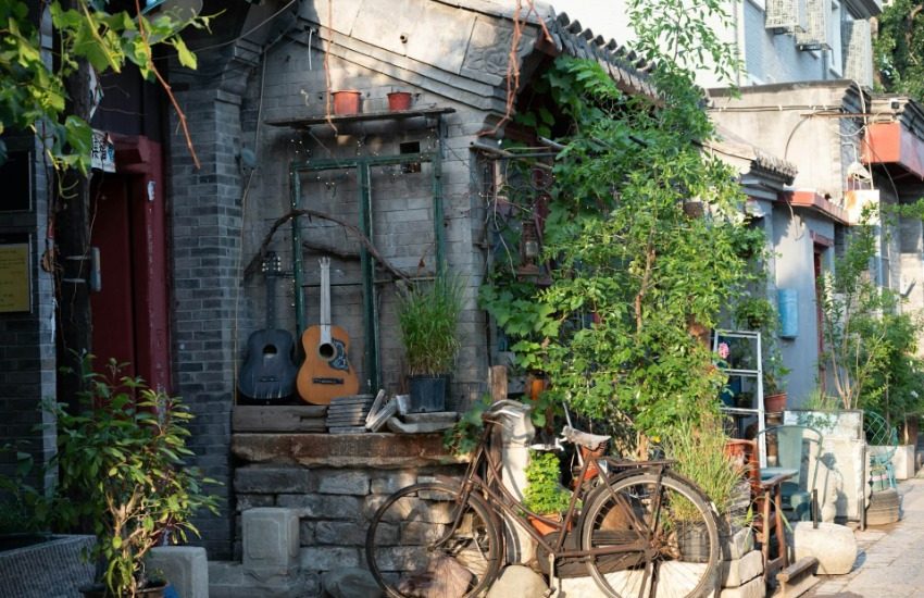The entrance of a courtyard house (siheyuan)-Hutong Guide-Beijing At the entrance of a Beijing courtyard, there’s a bicycle and two guitars displayed.