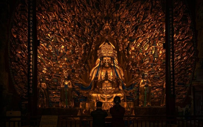 View-Dazu Rock Carvings-Chongqing At the Dazu Rock Carvings, tourists are kneeling and praying in front of the Thousand-Hand Guanyin.